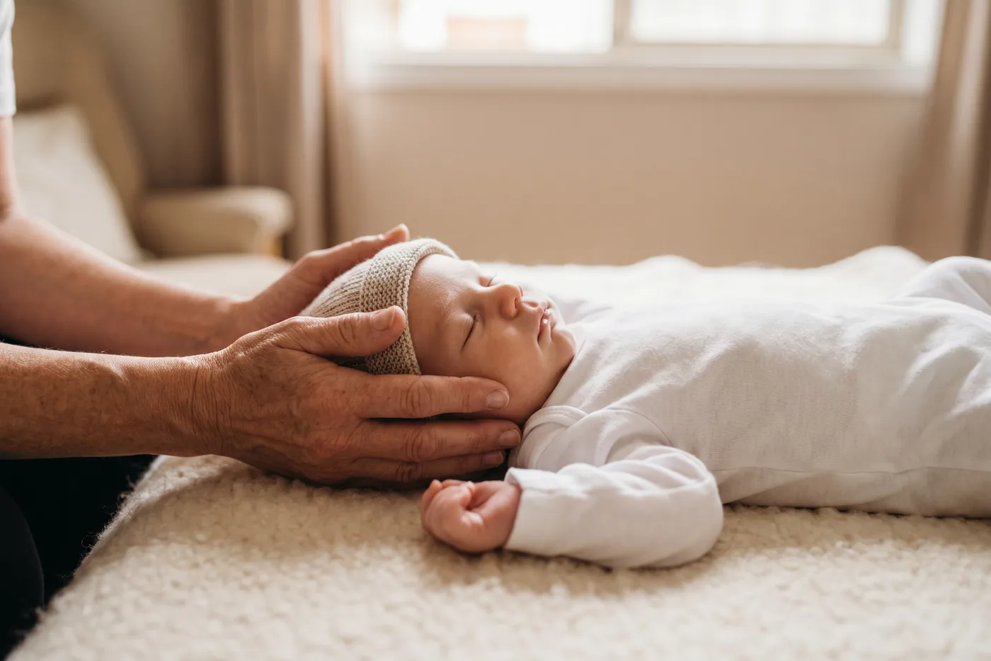 A practitioner’s hands gently cradling a calm baby’s head