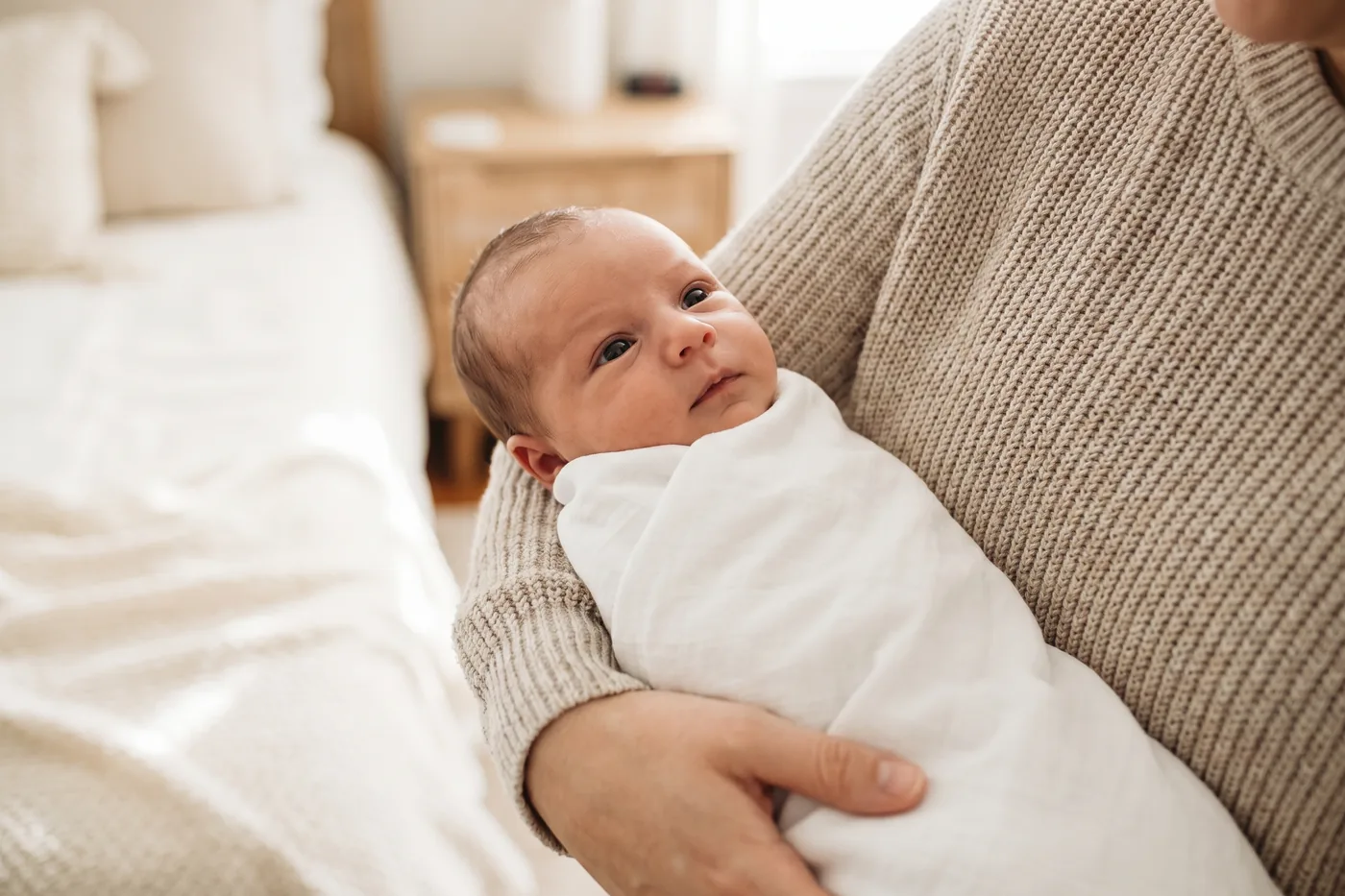 A newborn securely swaddled and held calmly in a parent’s arms