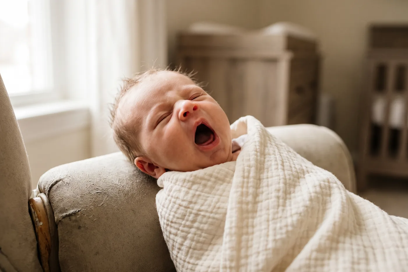 A newborn yawning widely, the tongue visible